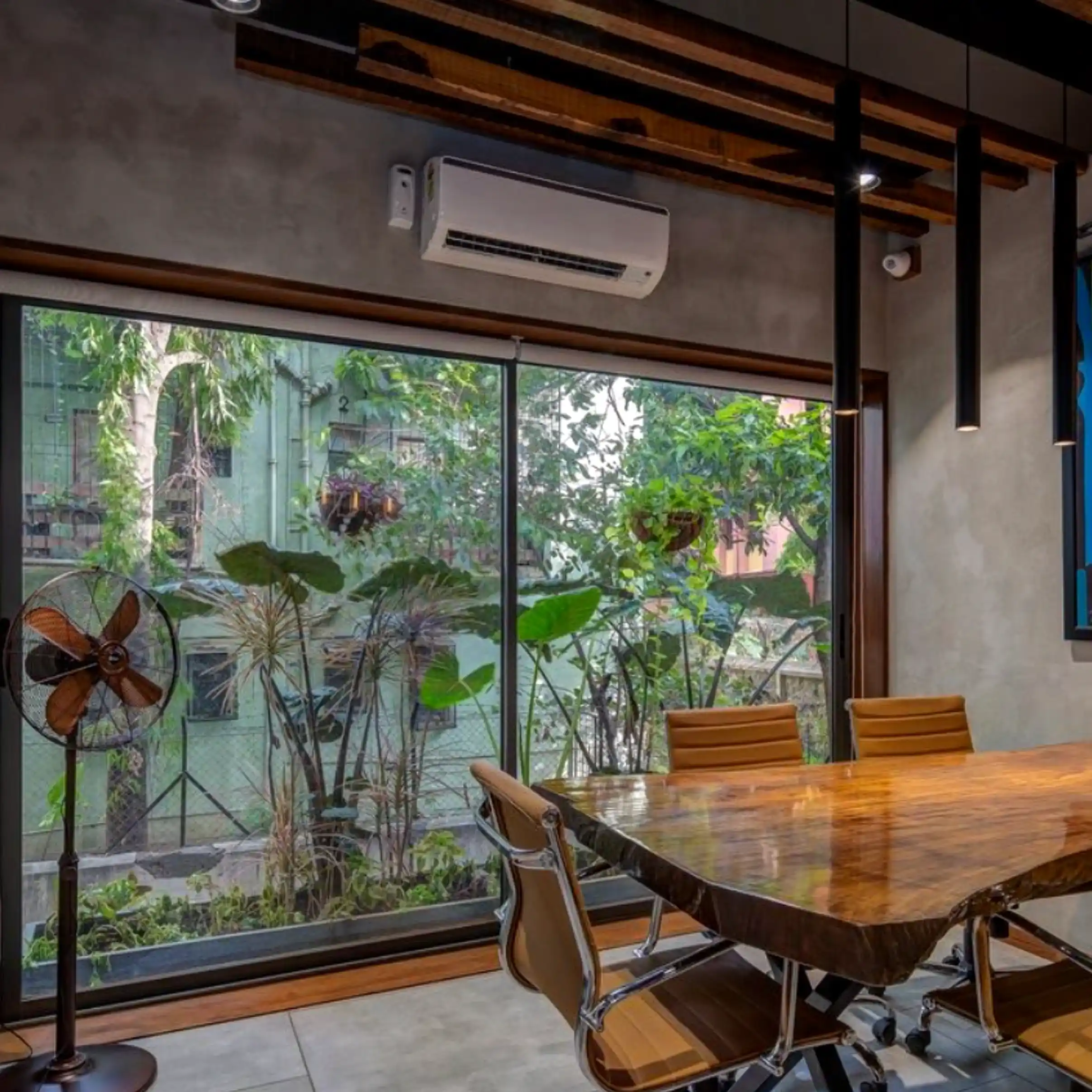 Meeting room with live-edge wood table, leather chairs, and garden view through glass