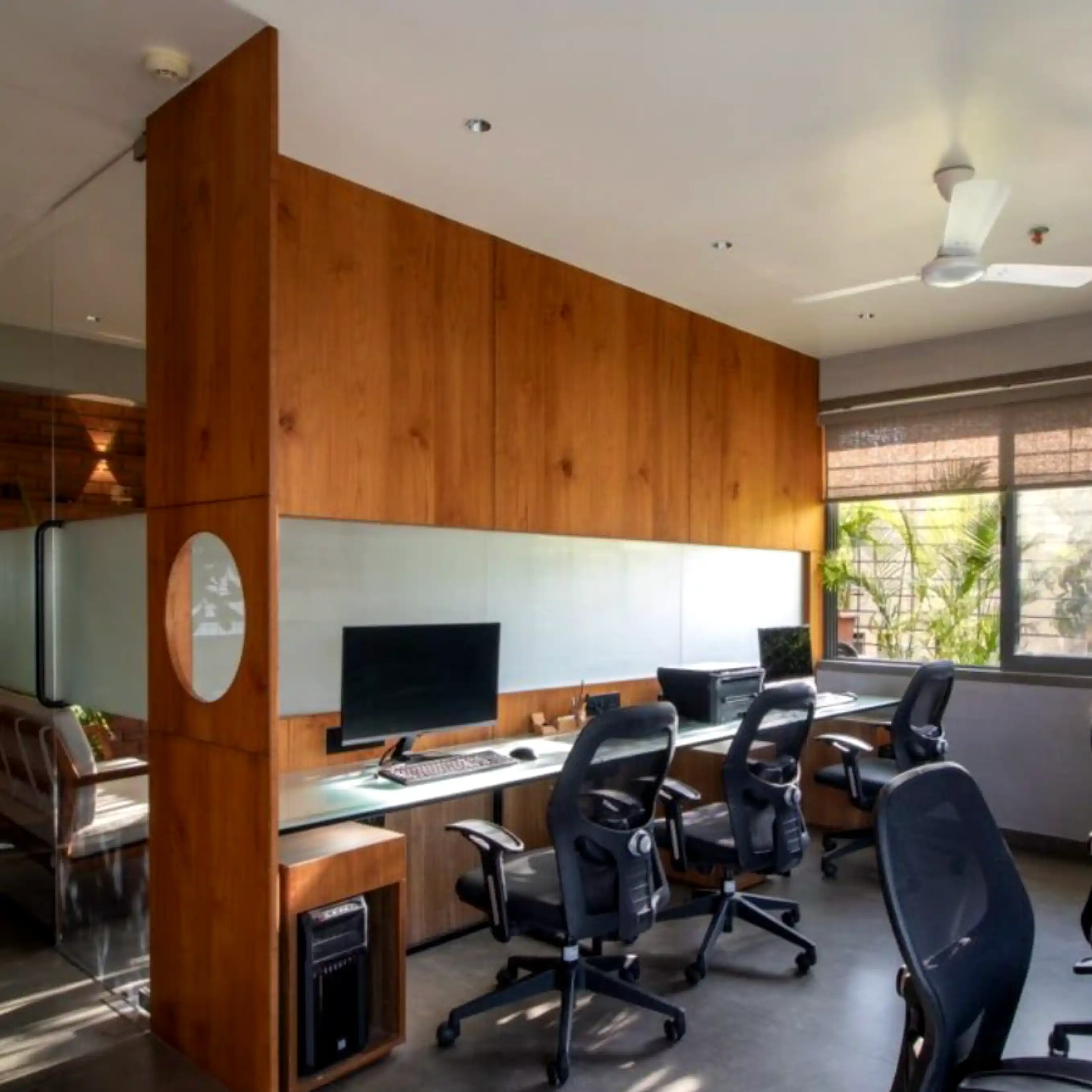 Open office with shared desks, wood cabinetry, and large windows